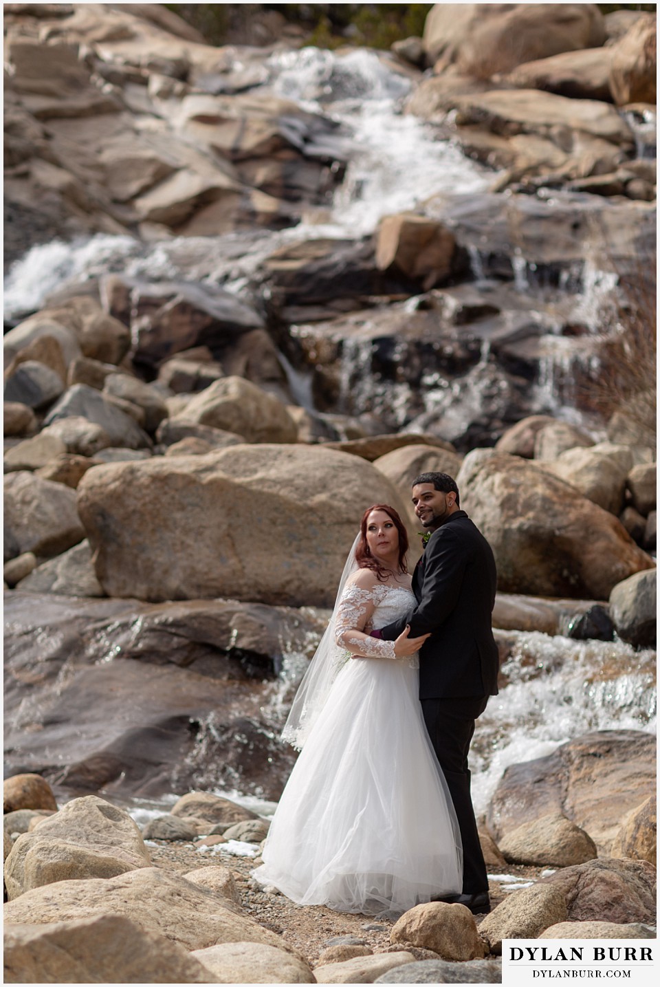spring colorado wedding couple standing by waterfall in spring