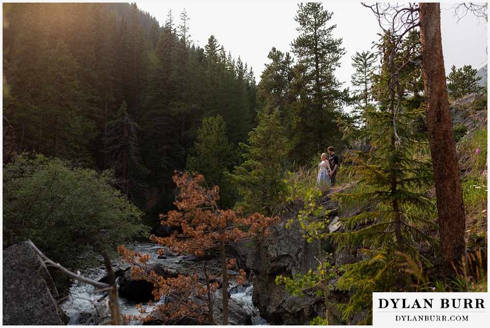 mountain adventure elopement wedding colorado wide view of bride and groom standing along river