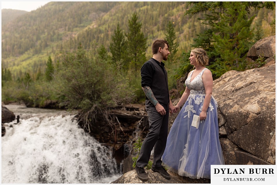 mountain adventure elopement wedding colorado groom saying his vows to his bride surrounded by waterfalls