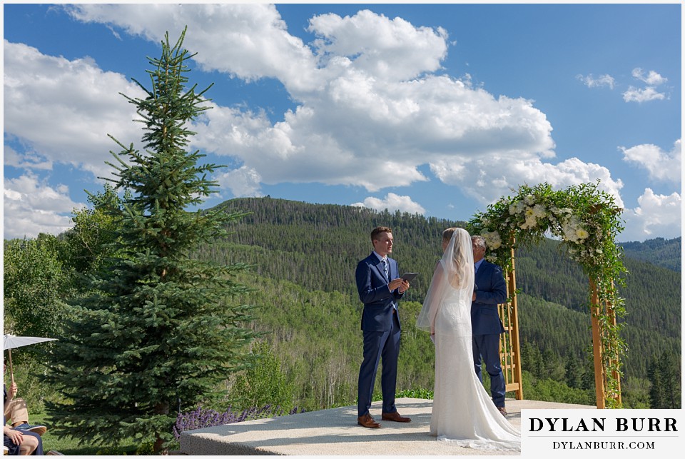 personal mountain home colorado wedding groom reading vows to his bride in mountains