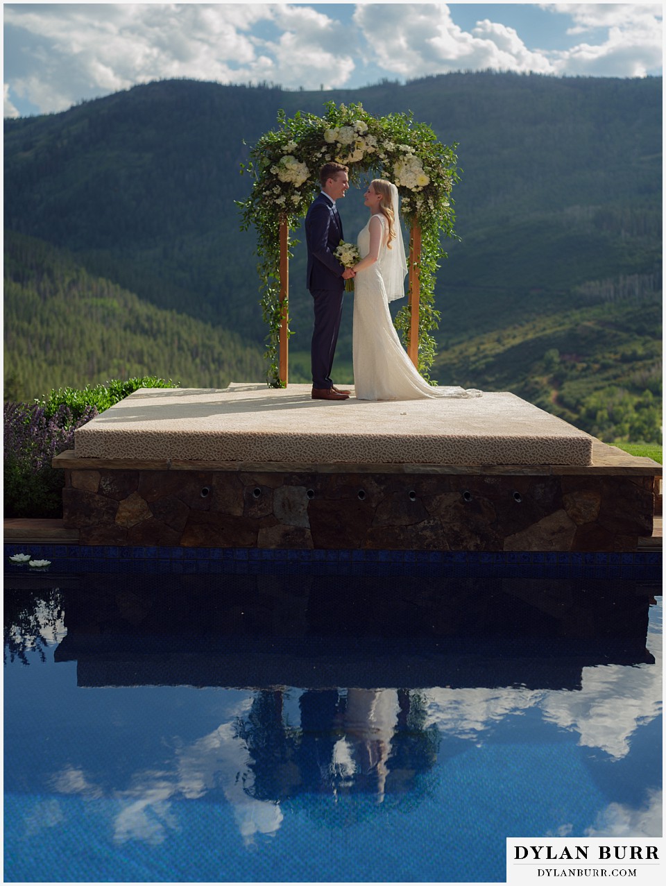personal mountain home colorado wedding couple standing in front of arbor with a reflection below in the pool