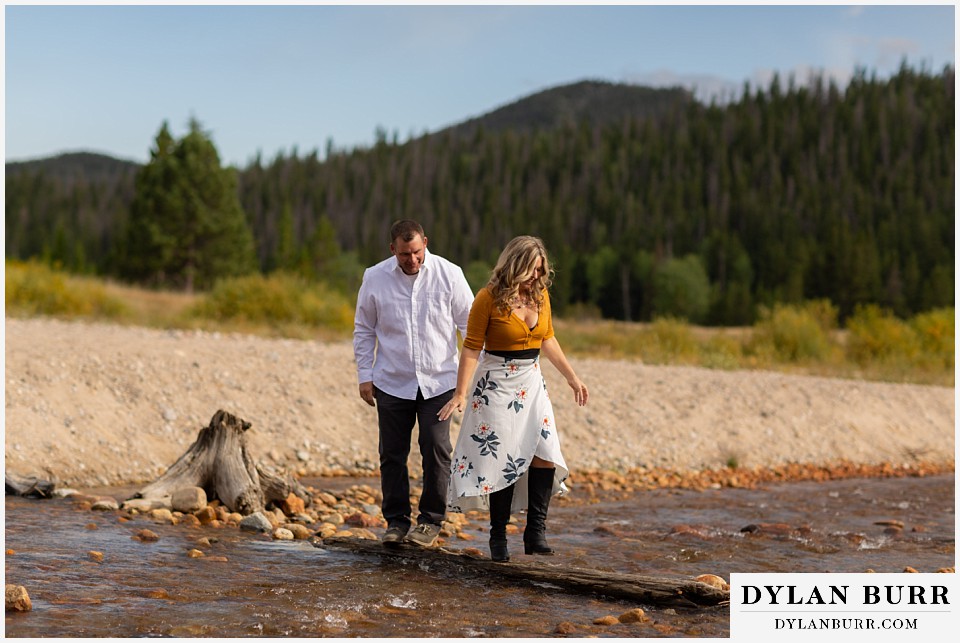 rocky mountain national park elopement wedding bride and groom walking across river on log