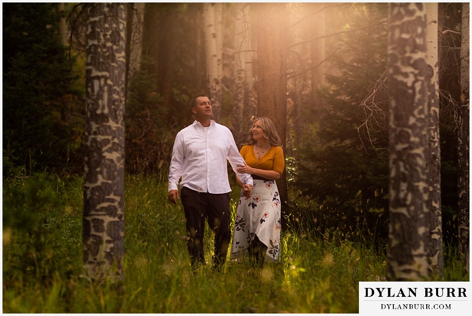 rocky mountain national park elopement wedding bride and groom walking in forest with sun glow