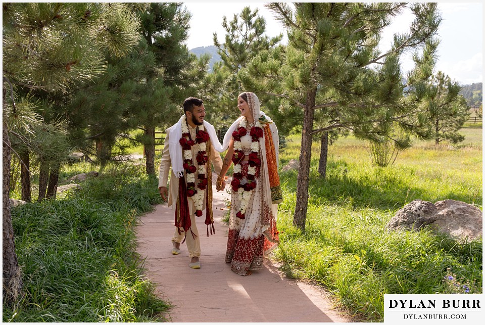 spruce mountain ranch wedding indian wedding bride and groom walking together down path in pine trees