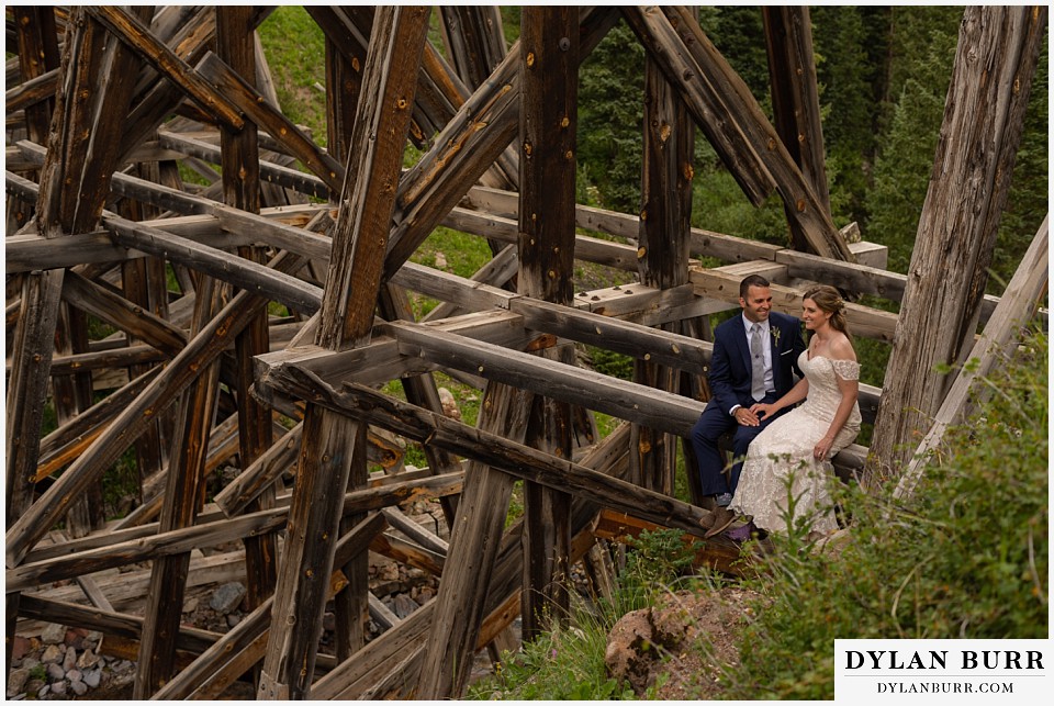 telluride colorado elopement wedding adventure bride and groom sitting on giant old wooden train bridge